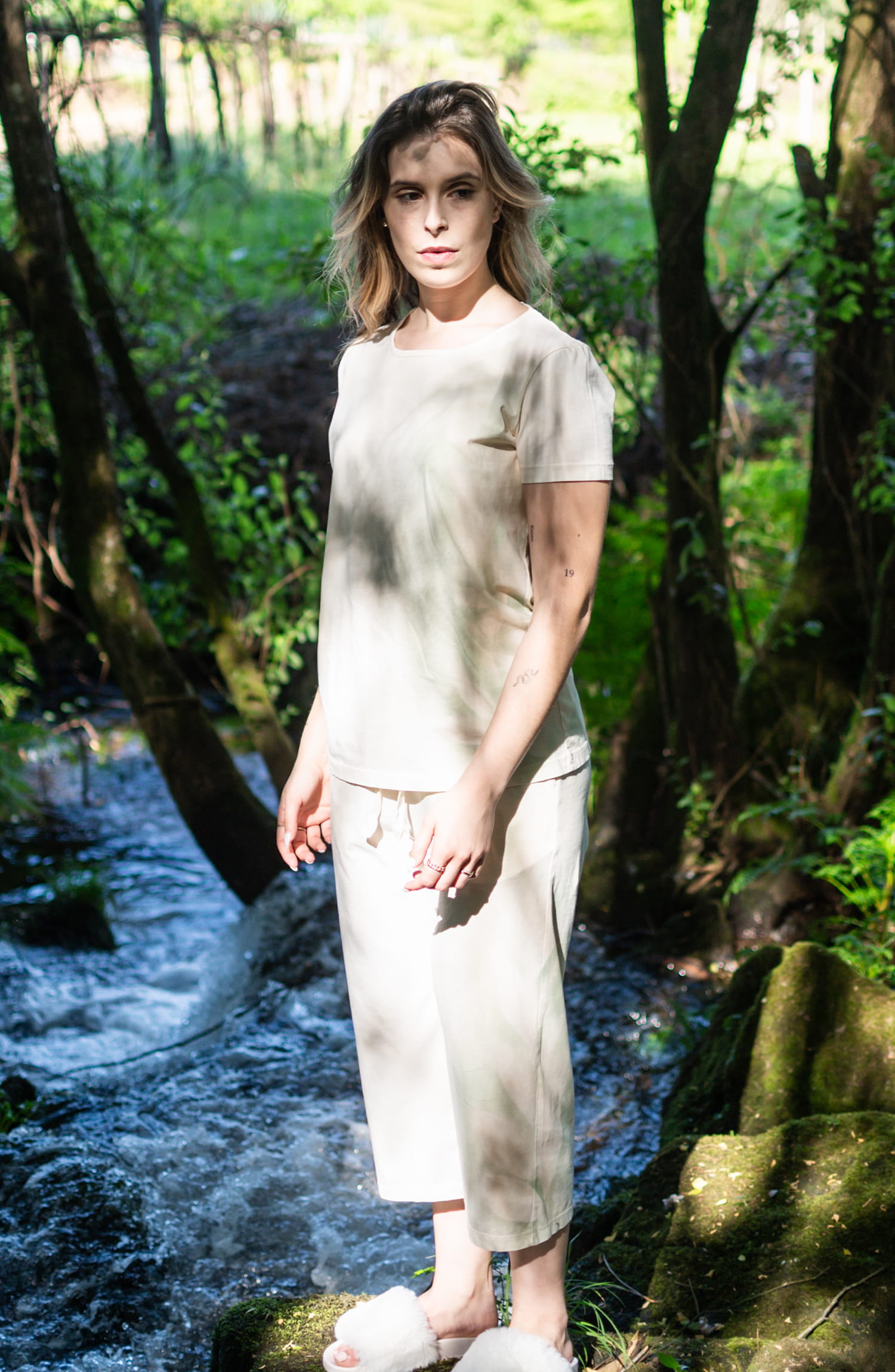 Modelo a usar o pijama Floralis Unus em algodão orgânico com efeitos de spray de folhas naturais de amoreira, foto de lifestyle no exterior.