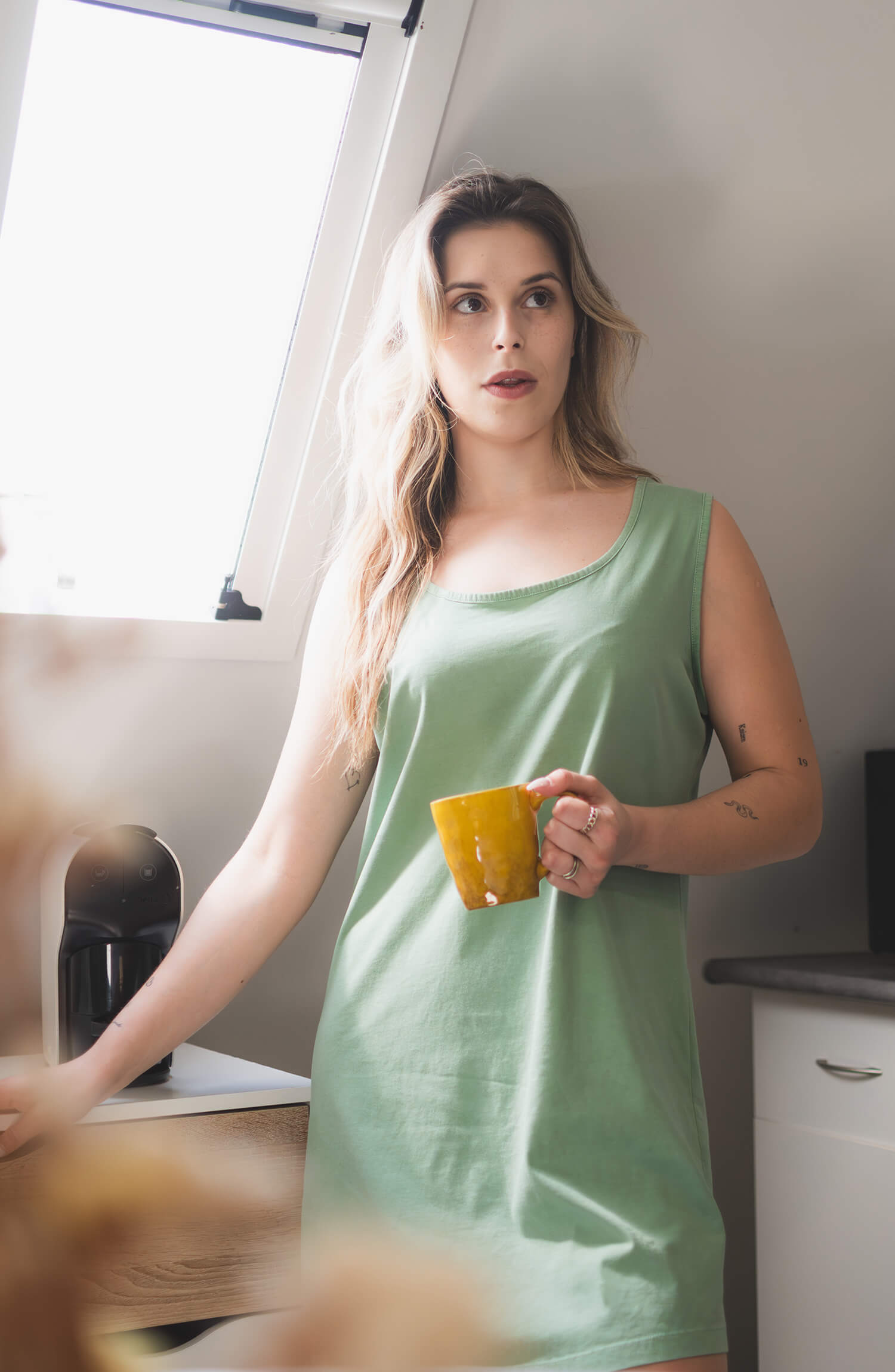 Model wearing the organic cotton Morus nightshirt, naturally dyed, holding a yellow mug.